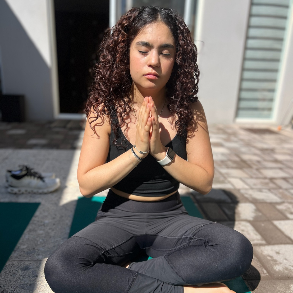 Mujer practicando meditación y mindfulness en posición de loto con los ojos cerrados.