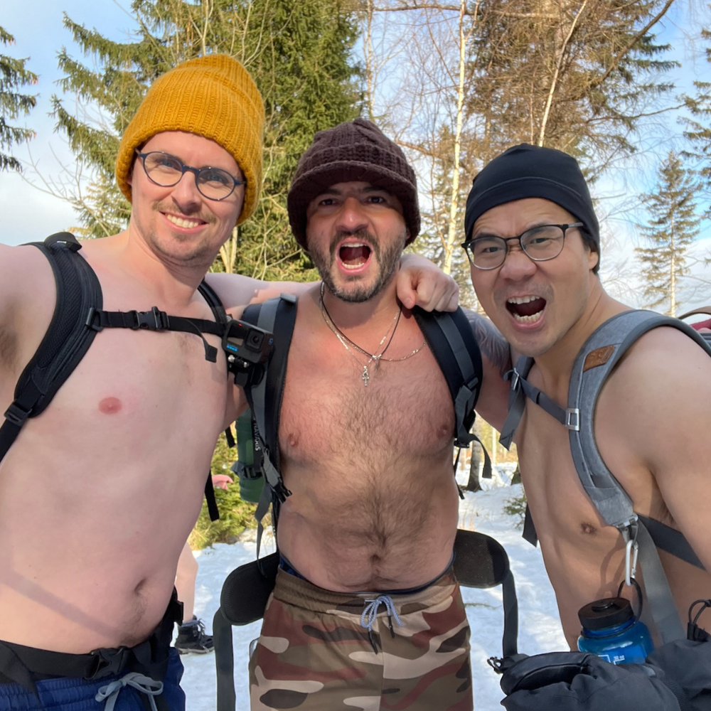 Richi Castro en el bosque nevado junto a dos compañeros de entrenamiento, todos sin camisa y mostrando energía y camaradería durante la práctica en frío.